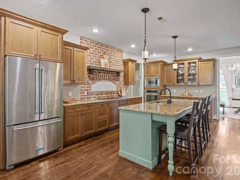 3143 James Plantation Drive, Denver, NC 28037.  MLS# CAR4366315, YatesRealty ID 18210. Custom kitchen with granite countertops, large island, and striking exposed brick accent wall.