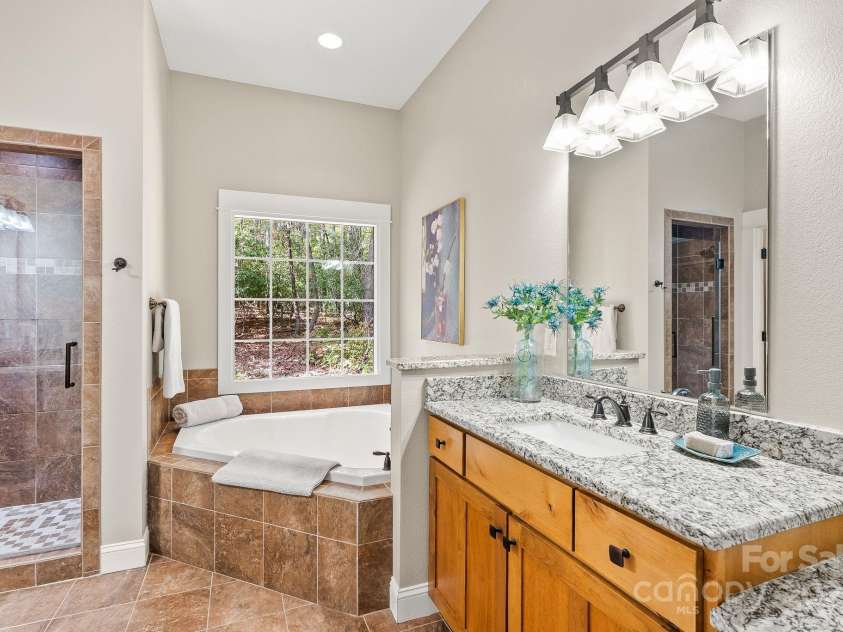 605 Salola Lane, Brevard, NC 28712.  MLS# CAR4312088, YatesRealty ID 18227. The spacious primary bath boasts a soaker tub & walk-in shower