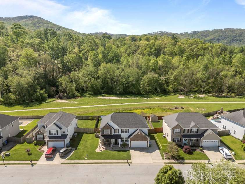 347 Wildbriar Road, Fletcher, NC 28732.  MLS# CAR4250812, YatesRealty ID 18254. A breathtaking aerial view showcases the home nestled against a stunning mountain backdrop, offering a rare blend of natural beauty and privacy