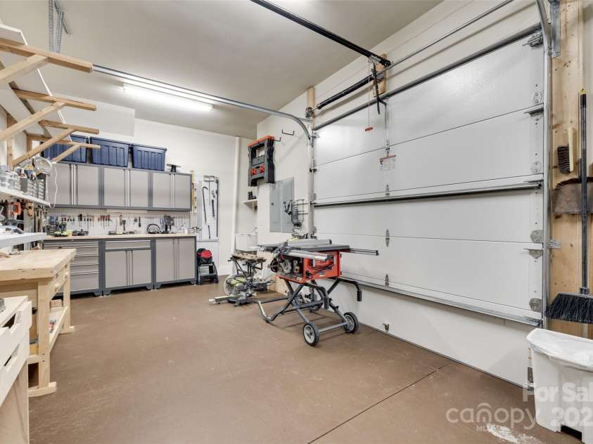 18311 Rosapenny Road, Charlotte, NC 28278.  MLS# CAR4256637, YatesRealty ID 18305. Well-organized workshop space with built-in shelving, ample storage, and double garage doors for easy entry and equipment use.