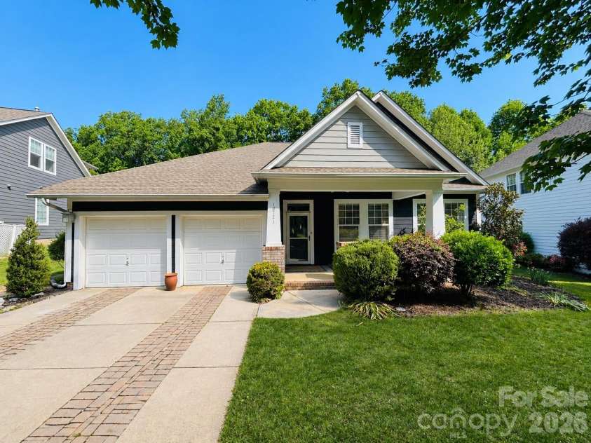 18721 The Commons Boulevard, Cornelius, NC 28031.  MLS# CAR4373232, YatesRealty ID 18371. Charming Ranch style home with a welcoming front porch, two-car garage, and beautifully maintained landscaping, all set beneath mature trees in a peaceful neighborhood.