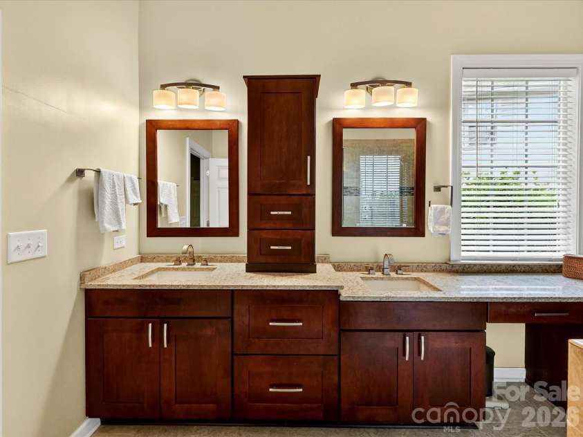 18721 The Commons Boulevard, Cornelius, NC 28031.  MLS# CAR4373232, YatesRealty ID 18371. Luxurious primary bath featuring dual vanities, granite countertops, and a spacious walk-in tiled shower with glass enclosure.