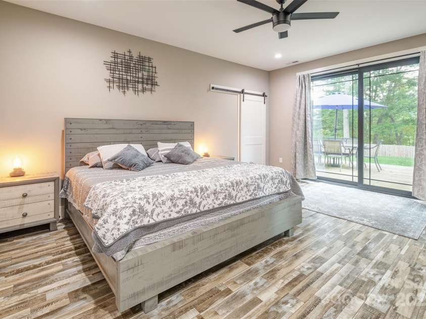 45 Erin Glen Court, Fairview, NC 28730.  MLS# CAR4239316, YatesRealty ID 18382. Primary bedroom with office space to the right of the bed and sliders leading out the large back deck