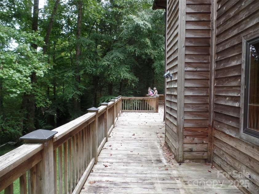 721 Kuenzel Eller Drive, Millers Creek, NC 28651.  MLS# CAR4179124, YatesRealty ID 184. View of large deck and large hardwood trees for shade. Owner looking toward the River through the trees.