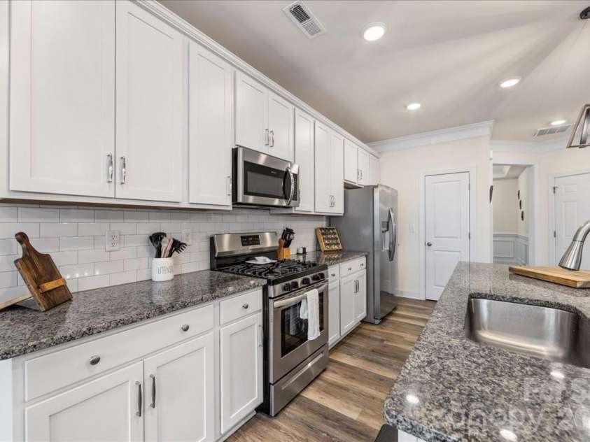 5923 Hampstead Pond Lane, Matthews, NC 28105.  MLS# CAR4340634, YatesRealty ID 18474. Kitchen includes granite countertops, tile backsplash, and gas range.