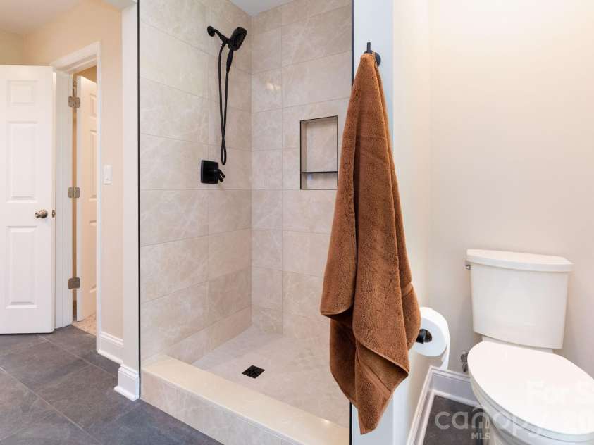 68 Sigmon Road, Fletcher, NC 28732.  MLS# CAR4336800, YatesRealty ID 18650. Beautifully tiled walk-in shower with modern finishes and glass enclosure.