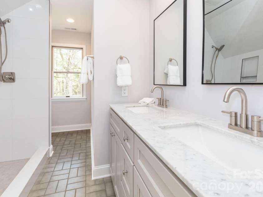68 Sigmon Road, Fletcher, NC 28732.  MLS# CAR4336800, YatesRealty ID 18650. Beautifully updated bathroom featuring dual vanities, marble countertops, and a tiled walk-in shower.