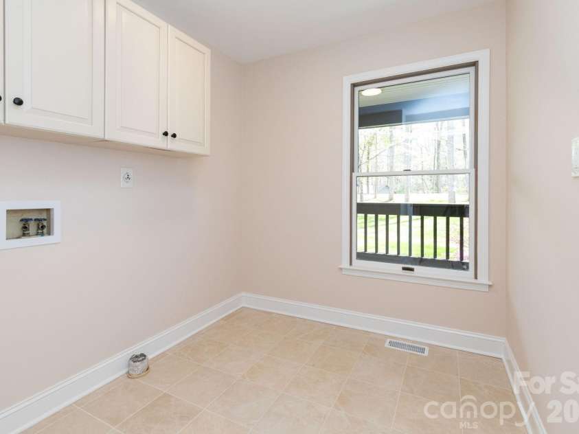 68 Sigmon Road, Fletcher, NC 28732.  MLS# CAR4336800, YatesRealty ID 18650. Convenient main-level laundry room with cabinetry and natural light for added functionality.