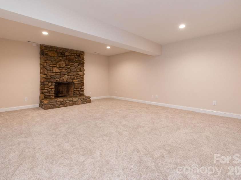 68 Sigmon Road, Fletcher, NC 28732.  MLS# CAR4336800, YatesRealty ID 18650. Expansive lower-level living area with cozy stone fireplace—perfect for entertaining, movie nights, or a game room.