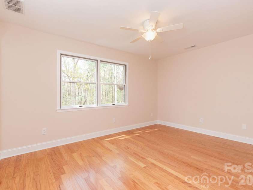 68 Sigmon Road, Fletcher, NC 28732.  MLS# CAR4336800, YatesRealty ID 18650. Light-filled bedroom with beautiful hardwood flooring and serene wooded views from the windows.