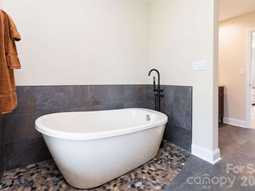 68 Sigmon Road, Fletcher, NC 28732.  MLS# CAR4336800, YatesRealty ID 18650. Relaxing soaking tub with tile surround—perfect for unwinding after a long day.