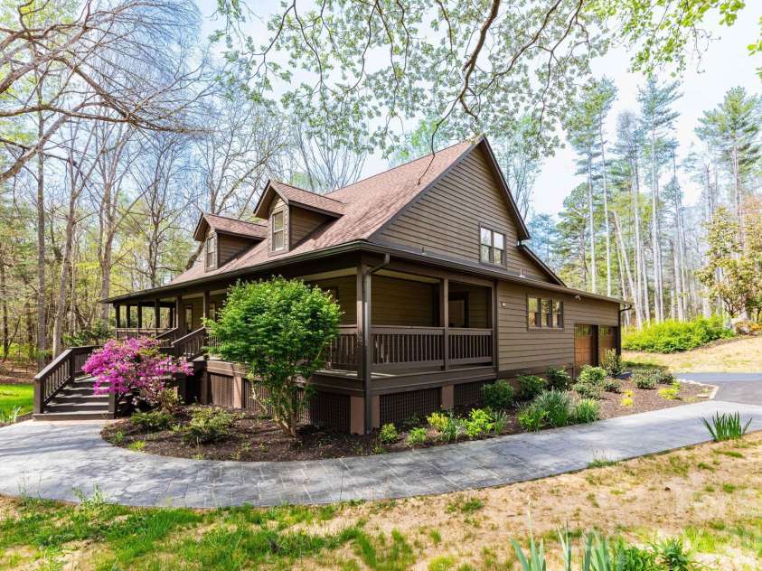 68 Sigmon Road, Fletcher, NC 28732.  MLS# CAR4336800, YatesRealty ID 18650. Side view showcasing the home's natural setting and well-maintained landscaping, blending seamlessly into the surrounding woods.