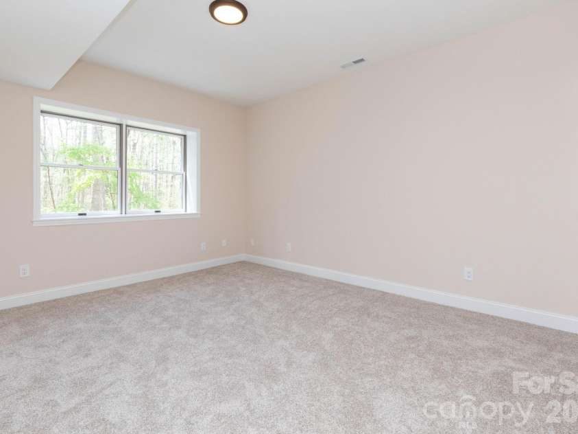 68 Sigmon Road, Fletcher, NC 28732.  MLS# CAR4336800, YatesRealty ID 18650. Spacious bedroom with plush carpeting and large windows bringing in natural light and peaceful views.