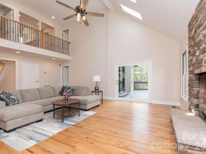 68 Sigmon Road, Fletcher, NC 28732.  MLS# CAR4336800, YatesRealty ID 18650. Spacious living room with soaring vaulted ceilings, skylights, and a stunning floor-to-ceiling stone fireplace.