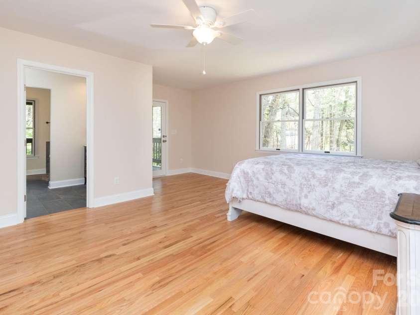 68 Sigmon Road, Fletcher, NC 28732.  MLS# CAR4336800, YatesRealty ID 18650. Spacious primary bedroom with hardwood floors, abundant natural light, and direct access to the outdoor deck.