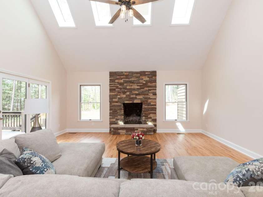 68 Sigmon Road, Fletcher, NC 28732.  MLS# CAR4336800, YatesRealty ID 18650. Stunning living room with vaulted ceilings, skylights, and a beautiful stone fireplace as the focal point.