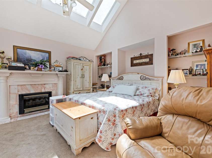 650 Creekside Drive, Maggie Valley, NC 28751.  MLS# CAR4335648, YatesRealty ID 18657. Ambience is key is the primary suite where natural light brightens the space accompanied by a cozy fireplace, built-in shelving and a cathedral ceiling with a bank of skylights