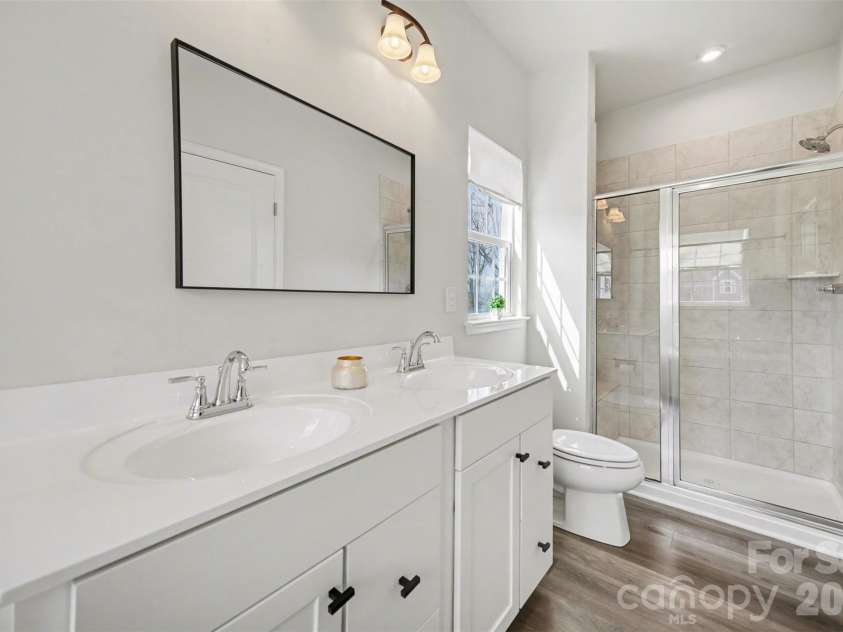 1211 May Apple Drive, Matthews, NC 28104.  MLS# CAR4349780, YatesRealty ID 18695. Bright primary bathroom with dual vanity and spacious walk-in shower