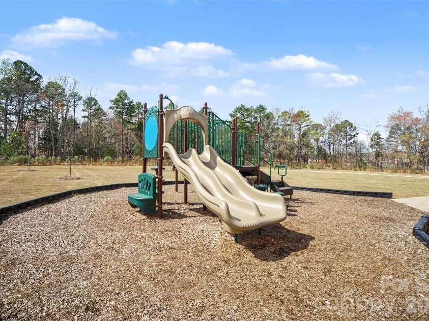 1211 May Apple Drive, Matthews, NC 28104.  MLS# CAR4349780, YatesRealty ID 18695. Community playground featuring a multi-slide play structure, surrounded by open green space.