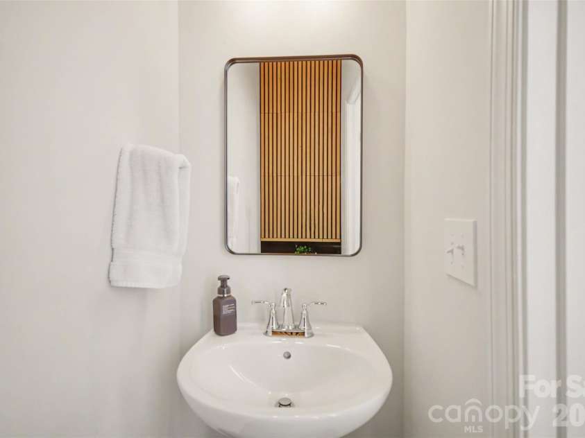 1211 May Apple Drive, Matthews, NC 28104.  MLS# CAR4349780, YatesRealty ID 18695. Half bath with modern pedestal sink & warm wood accent wall