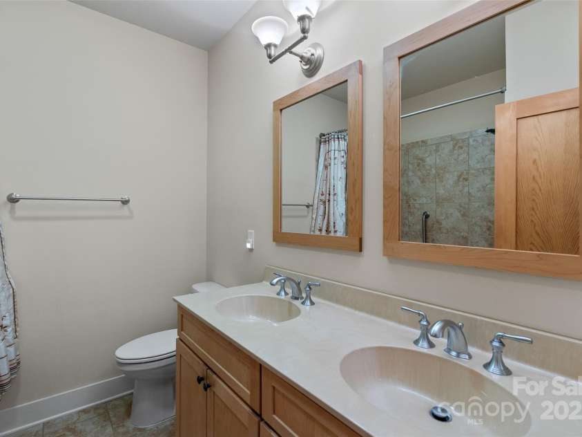 50 Mandolin Drive, Black Mountain, NC 28711.  MLS# CAR4264408, YatesRealty ID 18743. The roomy lower level bathroom has a dual sink vanity and a huge whirlpool jet tub, perfect for guests and family. It also includes a shower.