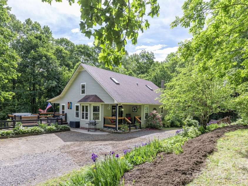 1645 Hickory Springs Road, Burnsville, NC 28714.  MLS# CAR4260205, YatesRealty ID 18810. The back side of the house surrounded by flowers and trees