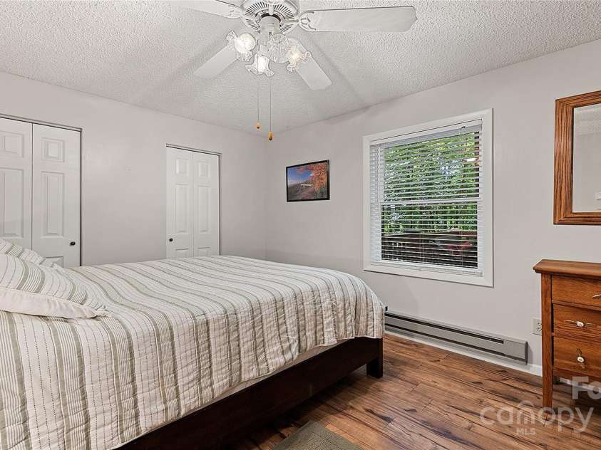120 Blue Jay Loop, Maggie Valley, NC 28751.  MLS# CAR4242766, YatesRealty ID 18880. This bright and peaceful bedroom offers a serene retreat with soft natural light, a ceiling fan for year-round comfort, dual closets for ample storage, and warm flooring that enhances the cozy mountain charm.
