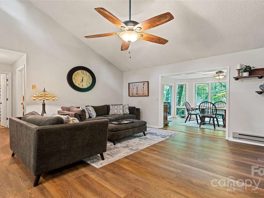 120 Blue Jay Loop, Maggie Valley, NC 28751.  MLS# CAR4242766, YatesRealty ID 18880. This inviting living space features vaulted ceilings, rich wood flooring, and a seamless flow into a sunlit dining area with forest views.