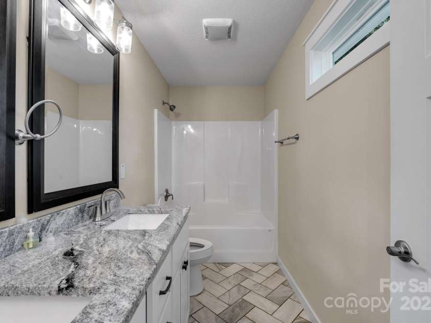 123 Dapple Road, Candler, NC 28715.  MLS# CAR4257282, YatesRealty ID 18892. Primary Bedroom Bath with granite double vanity countertop and herringbone tile