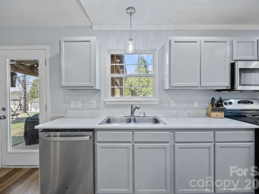 107 Panther Creek Road, Troutman, NC 28166.  MLS# CAR4356837, YatesRealty ID 18981. Bright and functional sink area featuring updated hardware and seamless integration with the modern grey cabinetry and tiled backsplash.