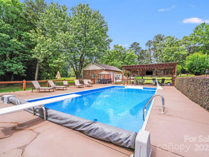 211 Drive Inn Road, Locust, NC 28097.  MLS# CAR4265447, YatesRealty ID 19009. Huge automatic covered pool with diving board redone recently per seller equipped with fencing around the whole pool and enough concrete patio and decking for multiple people to lay out swim and enjoy