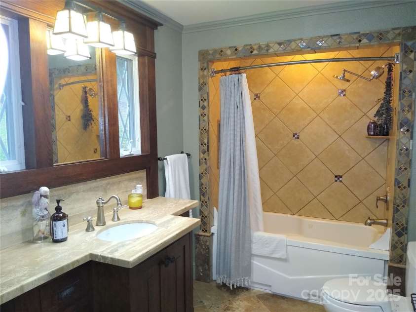 242 Birch Lane, Arden, NC 28704.  MLS# CAR4249293, YatesRealty ID 19164. Bathroom #2 with custom cabinet and a garden tub and tiled surround.