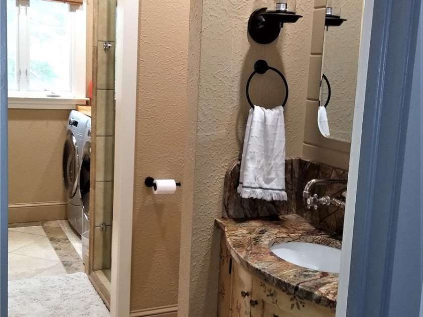 242 Birch Lane, Arden, NC 28704.  MLS# CAR4249293, YatesRealty ID 19164. Bathroom#3 with travertine stone floor, a custom granite countertop/sink and cabinet plus a shower and full laundry.