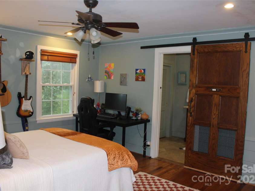 242 Birch Lane, Arden, NC 28704.  MLS# CAR4249293, YatesRealty ID 19164. Bedroom #2 Ensuite with hardwood floors and sliding barn door leading to the bathroom.