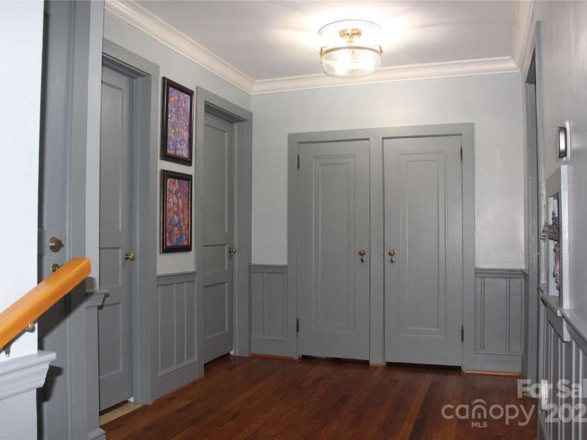 242 Birch Lane, Arden, NC 28704.  MLS# CAR4249293, YatesRealty ID 19164. Large Central Hallway with a two-door linen closet and paneled wainscoting leads to bedrooms #1 and #2 and their ensuite bathrooms.  The Walkup Attic doorway and Bathroom #3/Laundry doorway are on the left.