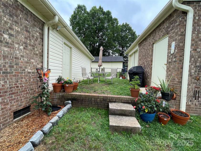 311 Tiffany Street, Concord, NC 28027.  MLS# CAR4264834, YatesRealty ID 19180. Area between the attached garage and detached storage shed for outdoor seating.