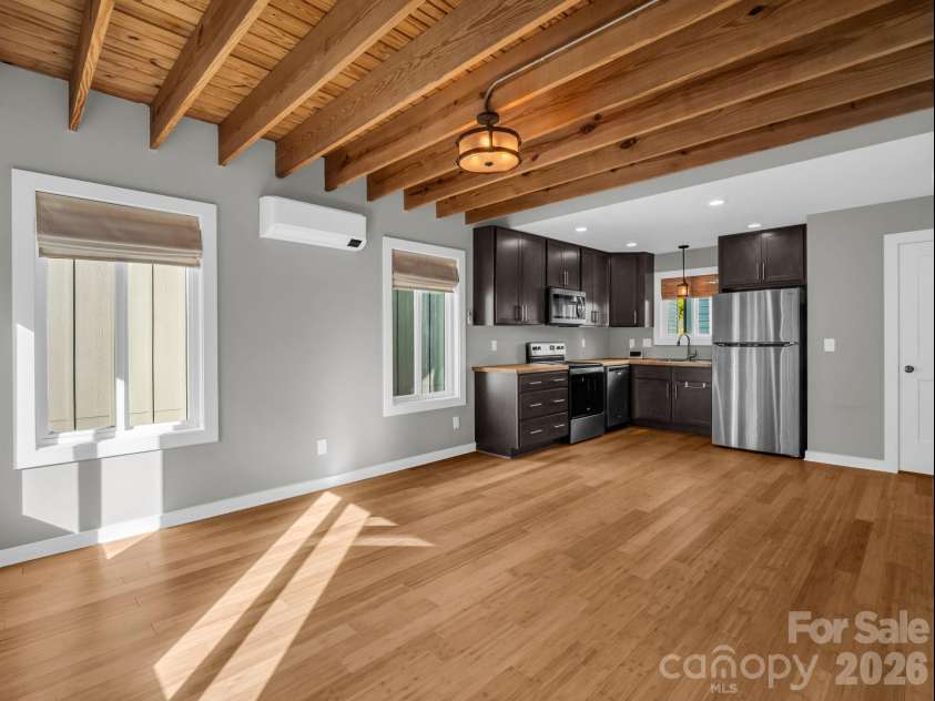9 Citra Street, Arden, NC 28704.  MLS# CAR4299774, YatesRealty ID 19197. Open-concept living space featuring warm wood flooring, exposed beam ceilings, and abundant natural light flowing into the modern kitchen.
