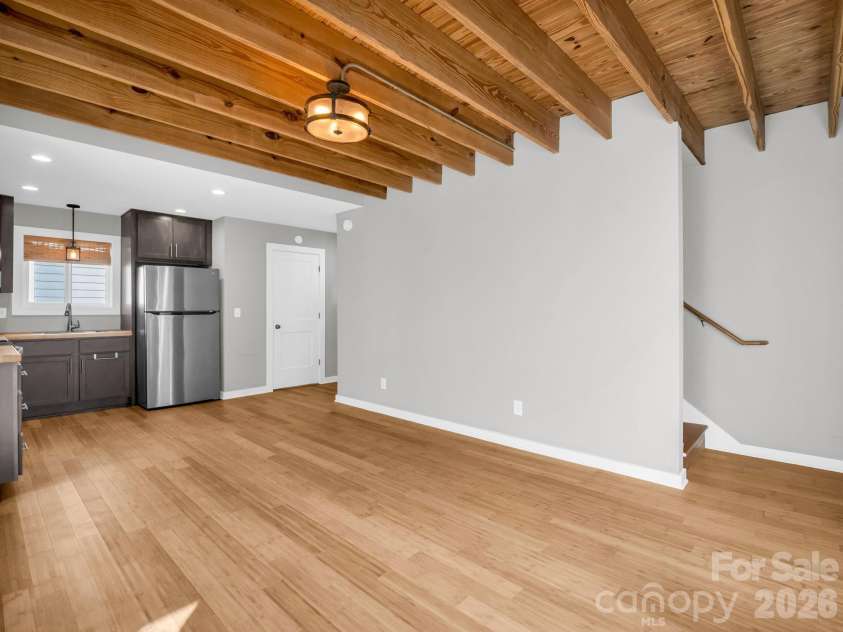 9 Citra Street, Arden, NC 28704.  MLS# CAR4299774, YatesRealty ID 19197. Open-concept living space featuring warm wood flooring, exposed beam ceilings, and abundant natural light flowing into the modern kitchen.