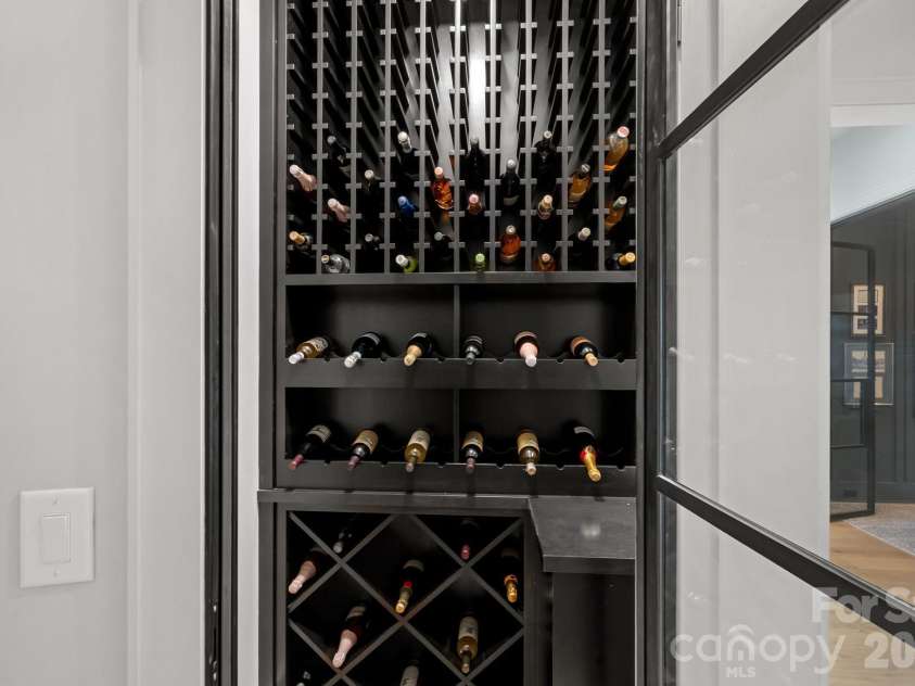 17811 Largo Place, Cornelius, NC 28031.  MLS# CAR4428601, YatesRealty ID 1945. A striking glass-enclosed wine display brings a bespoke, gallery-like element to the home.