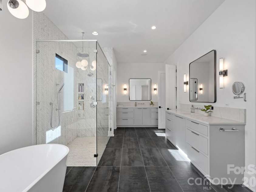 17811 Largo Place, Cornelius, NC 28031.  MLS# CAR4428601, YatesRealty ID 1945. Spa-inspired primary ensuite with dual vanities, a freestanding soaking tub and an oversized glass-enclosed shower with multiple shower fixtures and designer tilework.