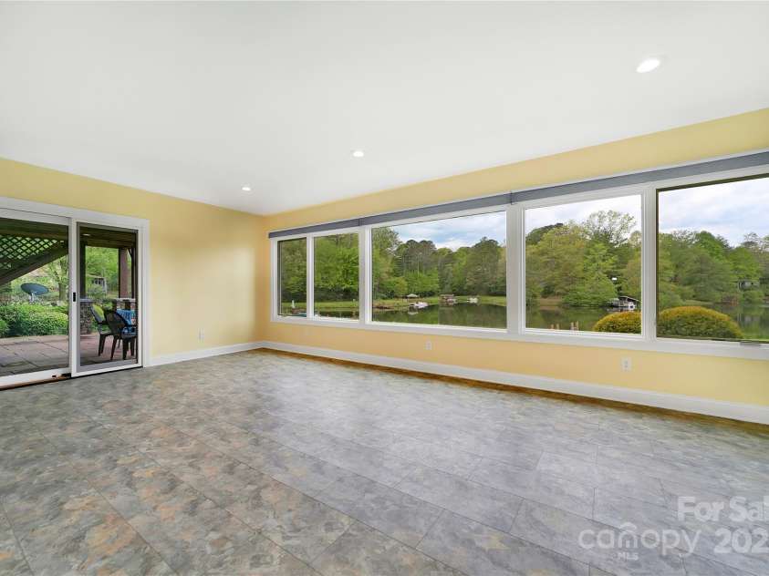 61 Tsataga Court, Brevard, NC 28712.  MLS# CAR4250347, YatesRealty ID 19462. The second primary bedroom is a stunning addition to the floorplan, featuring breathtaking lakefront views. Step out through the sliding glass doors and enjoy a refreshing swim in the lake each morning.