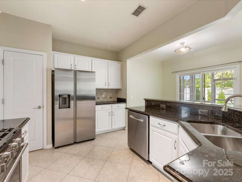 8603 Robinson Meadow Court, Charlotte, NC 28277.  MLS# CAR4265734, YatesRealty ID 19593. The Kitchen features a  pantry, white cabinetry, stainless steel appliances, granite countertops & a tile backsplash.