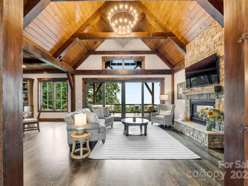 84 Meadow Top Lane, Hendersonville, NC 28792.  MLS# CAR4290136, YatesRealty ID 19615. From the entry, the great room unfolds in layers of beauty, its 22’ vaulted ceiling with chandelier leading the eye to the inviting deck and the serene, long-range mountain views beyond.