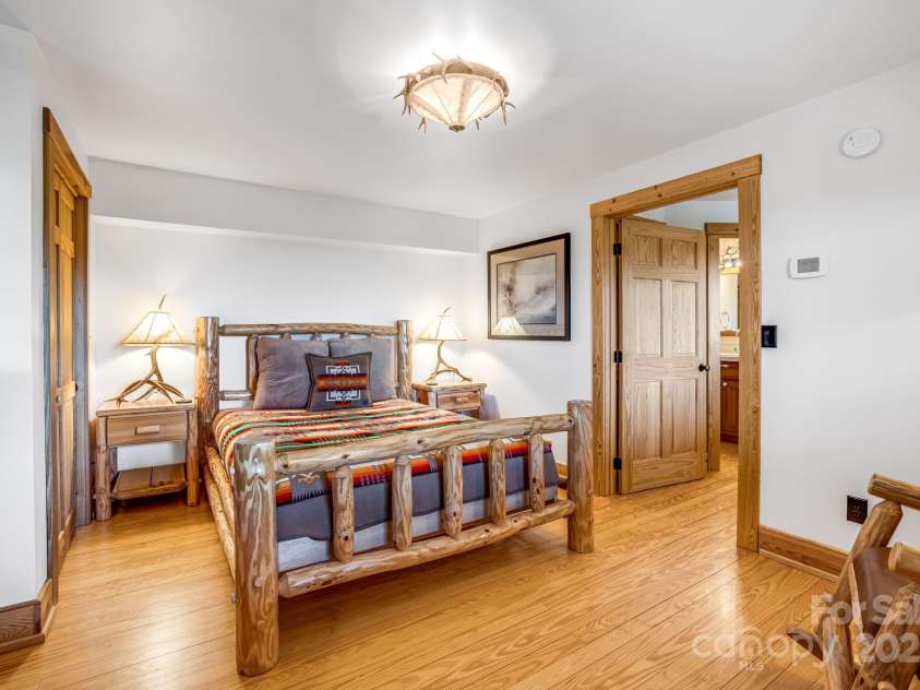 2399 El Miner Drive, Mars Hill, NC 28754.  MLS# CAR4259953, YatesRealty ID 19670. This rustic guest bedroom features a handcrafted log bed, antler-inspired lighting, and warm wood accents for a cozy mountain retreat.