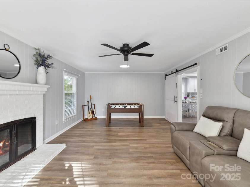 2315 Lawton Bluff Road, Charlotte, NC 28226.  MLS# CAR4255535, YatesRealty ID 19671. Spacious den off of entry that features a barn door, updated lighting, lots of windows & a wood-burning fireplace.