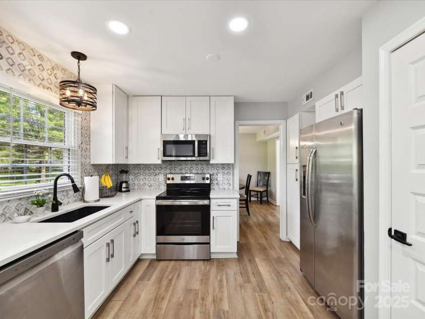 2315 Lawton Bluff Road, Charlotte, NC 28226.  MLS# CAR4255535, YatesRealty ID 19671. Stunning kitchen features white cabinetry, quartz ctops, ss appli, updated lighting & a beautiful tile backsplash!