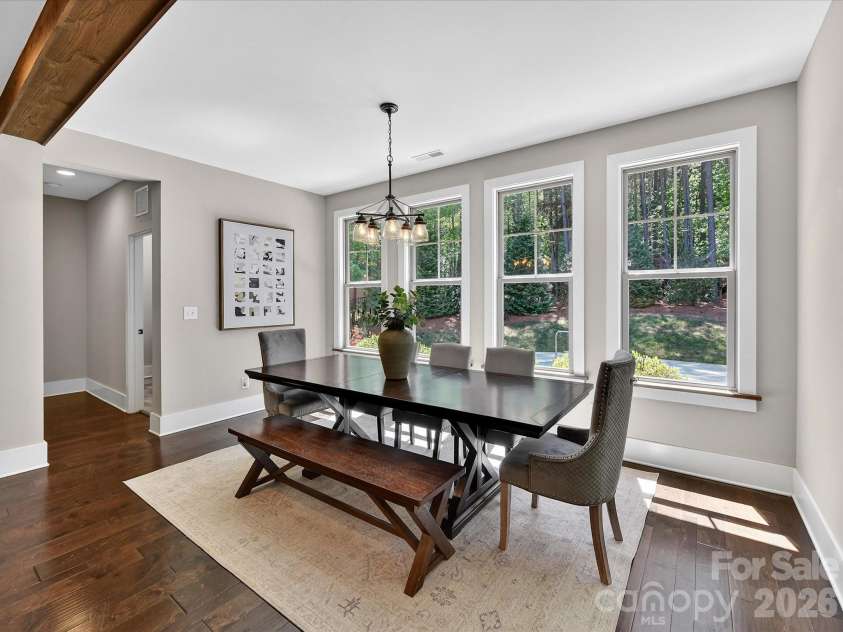 205 Streamwood Road, Troutman, NC 28166.  MLS# CAR4378738, YatesRealty ID 19708. Light-filled dining area features expansive windows with peaceful pool & wooded views, creating an inviting space for everyday meals and entertaining guests.