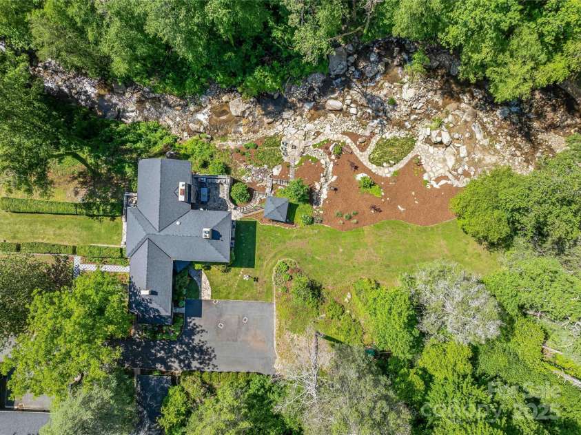 400 Kings Drive, Lake Lure, NC 28746.  MLS# CAR4264882, YatesRealty ID 19869. Aerial view of the house, patios, stream area and large parking area for guests.