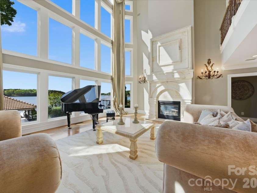 18103 Harbor Light Boulevard, Cornelius, NC 28031.  MLS# CAR4361515, YatesRealty ID 19890. Dramatic three-story great room with soaring ceilings, limestone fireplace, and wall of lake-facing windows