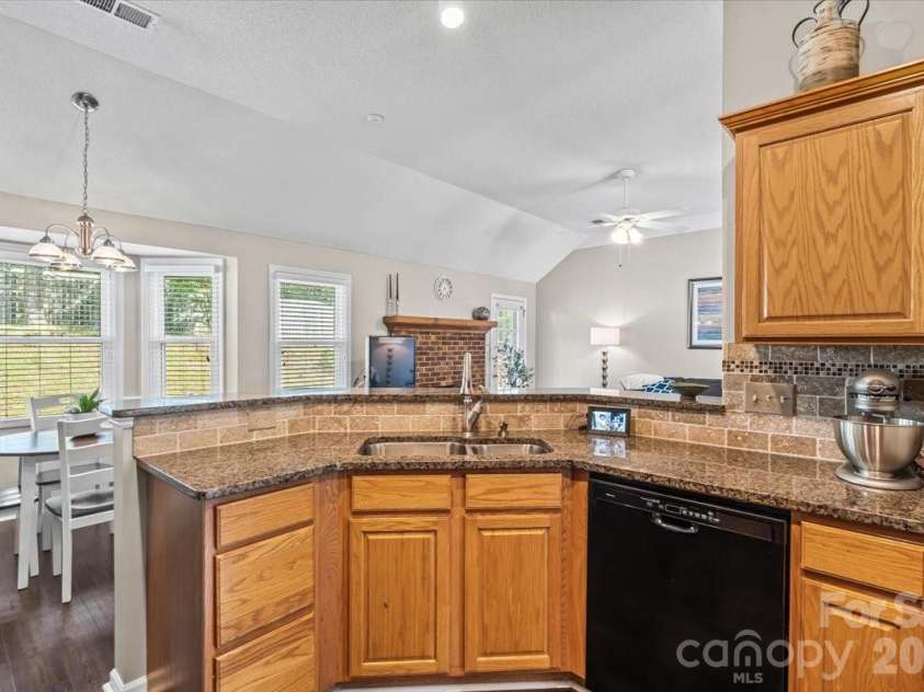 14413 John Beck Drive, Charlotte, NC 28273.  MLS# CAR4374623, YatesRealty ID 19941. The kitchen anchors the home with granite countertops, tile backsplash, and a breakfast bar peninsula